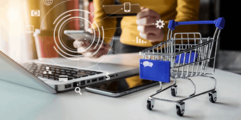pessoa utilizando o notebook para buscar Soluções Industriais e carrinho de compras a frente.