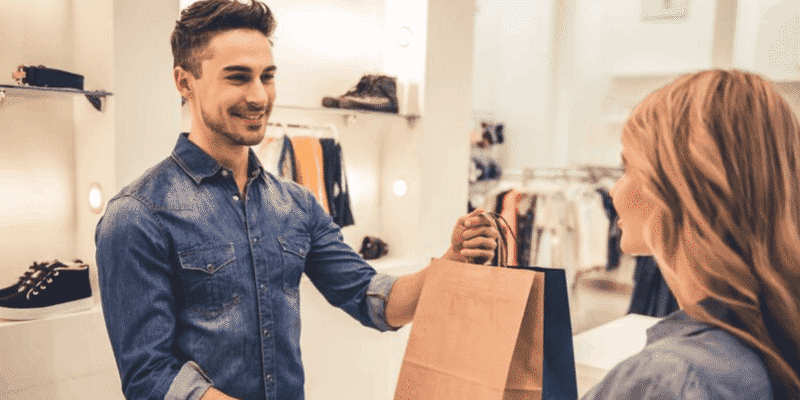 Cliente recebe uma sacola após fazer compra em loja.