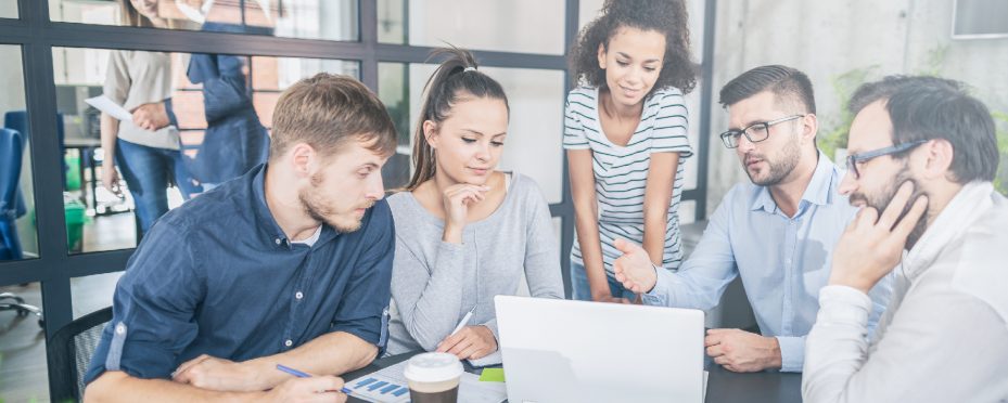 Grupo de pessoas reunidos em frente a um notebook analisando markteplace B2B.