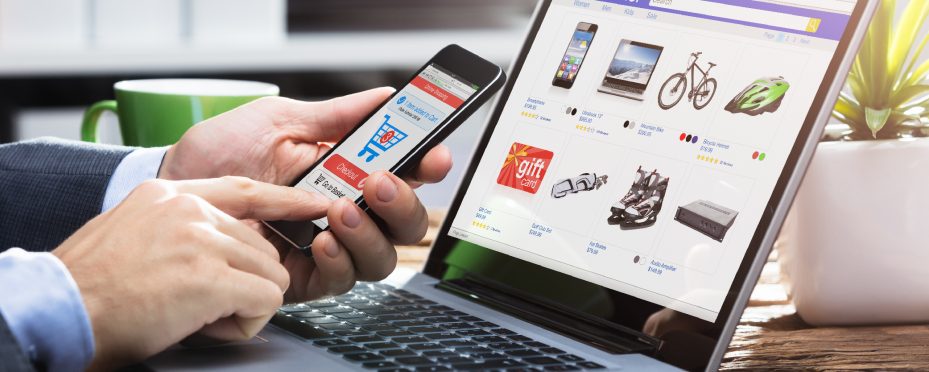 Notebook em site de vendas e mãos masculinas segurando celular em site de como vender na internet.