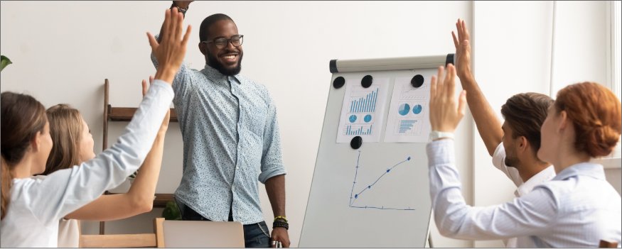Grupo de pessoas reunidas em frente a um flipchart para planejar ações de marketing e vendas.