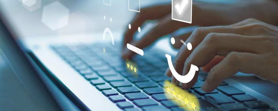 Mãos digitando sobre teclado e ícones de expressão de felicidade, tristeza com estrelas embaixo.
