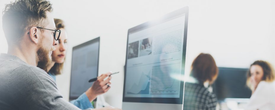 Homem e mulher analisam dados sobre como vender produtos em frente a tela do computador.