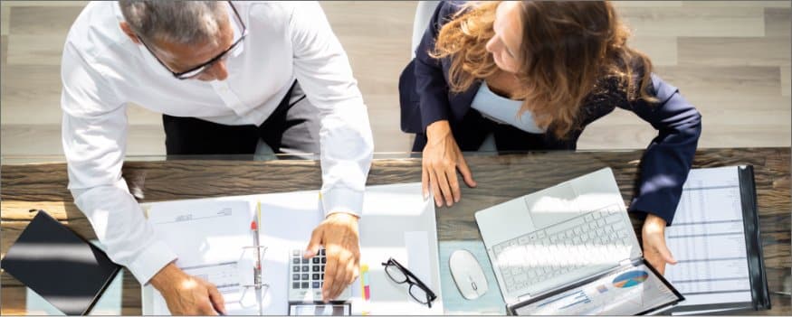 Homem e mulher sentados em frente a mesa com notebook e papéis para criar um diagnóstico empresarial.