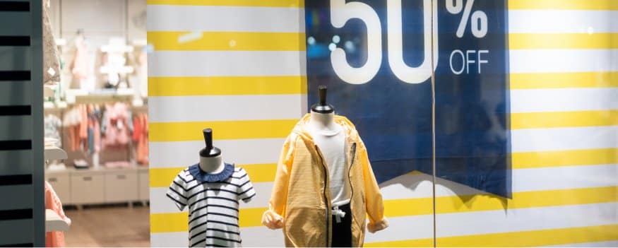 Vitrine de loja com camiseta e blusa de frio infantil em promoção de vendas.