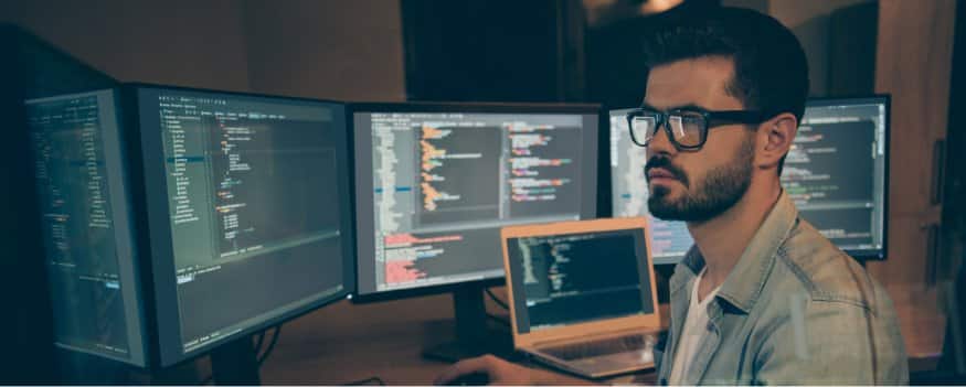 Homem em frente a telas de computador desenvolve site para empresa.