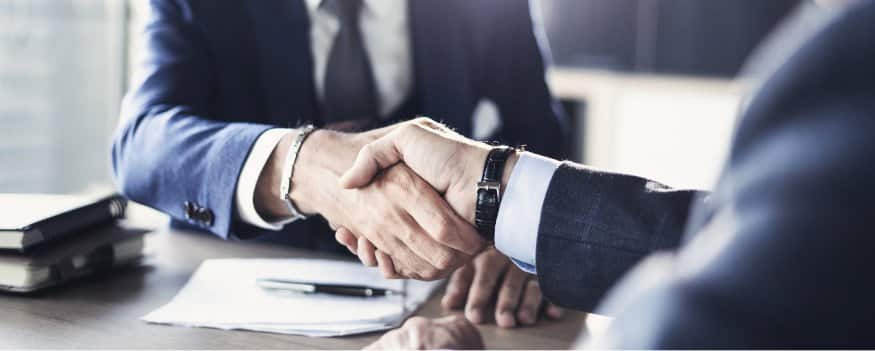 Dois homens de terno apertam as mãos em um acordo de vendas B2B.