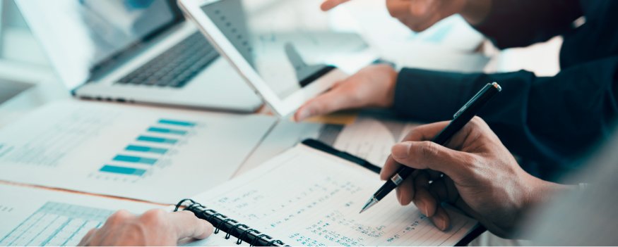 Homem escrevendo em agenda e outro segurando tablete para pesquisar o que é back office.