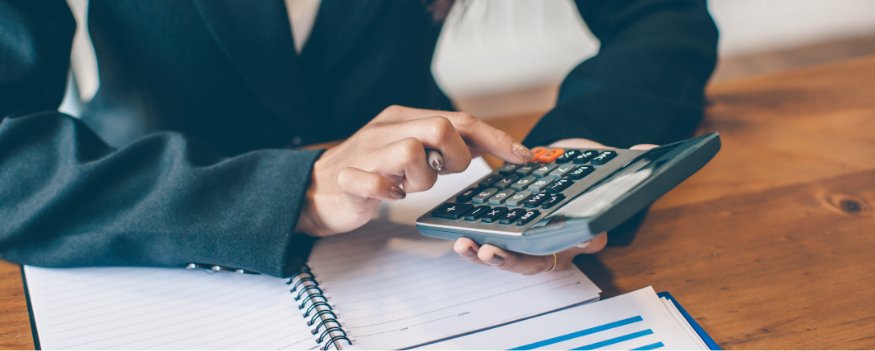 Mulher segurando calculadora em cima do caderno para fazer cálculo cmv.