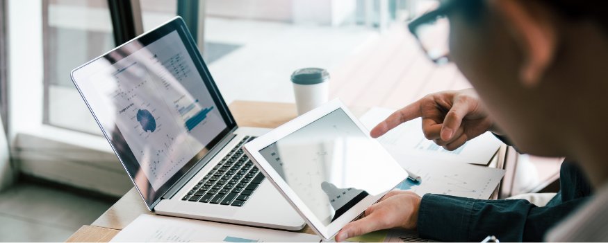 Homem em frente a notebook e tablet pesquisando por diagnóstico empresarial pronto.