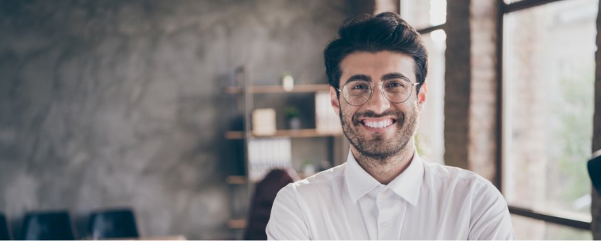 Homem de camisa branca e óculos sorrindo após descobrir o que é capital social