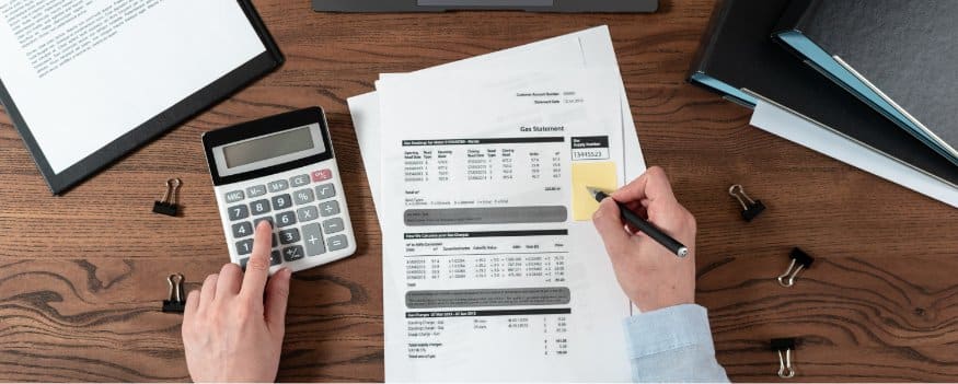 Homem realizando uma auditoria contábil com calculadora e papeis.