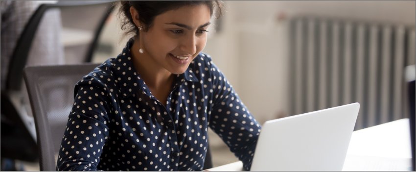 Mulher sorrindo em frente ao notebook após fazer cadastro de clientes.