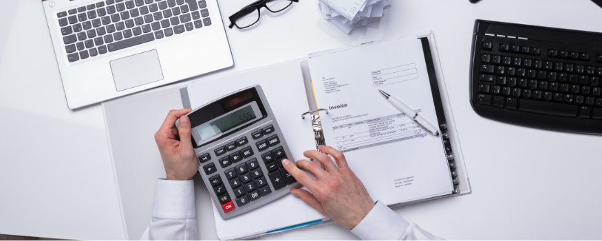 Uma pessoa fazendo contas em uma calculadora consultando papéis e notebook.