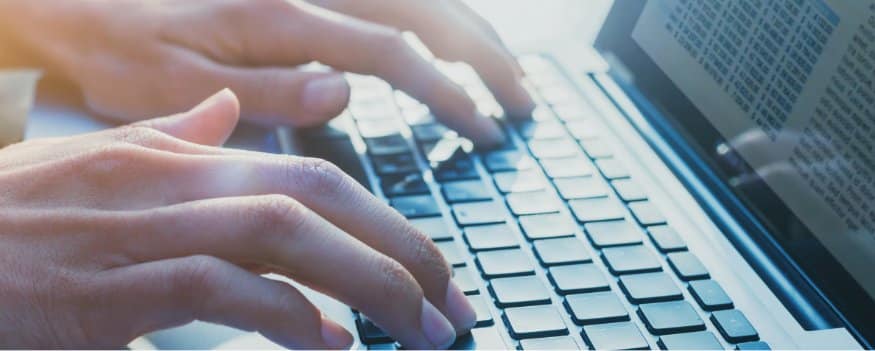 Mãos digitando em teclado de notebook para realizar conciliação bancária.