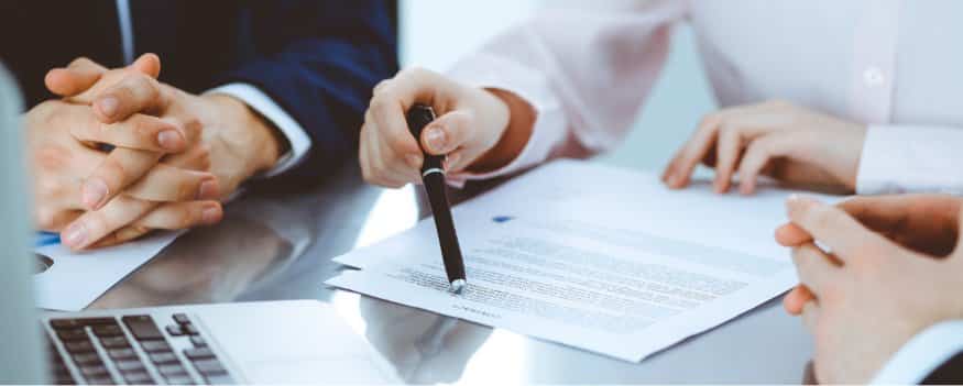 Três pessoas lendo e analisando o contrato social da empresa.
