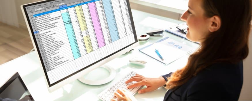 Mulher digitando valores em tabela para calcular o valuation da empresa.