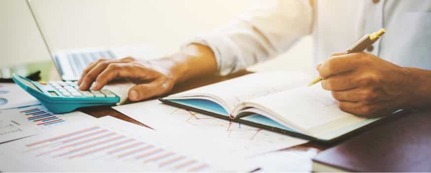 Homem fazendo anotações em caderno e usando calculadora para descobrir o valuation do seu negócio.