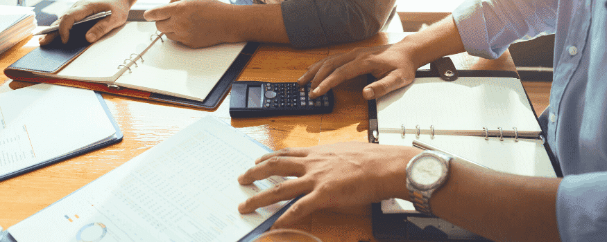 Duas pessoas fazendo contas e anotando informações sobre o PODC.