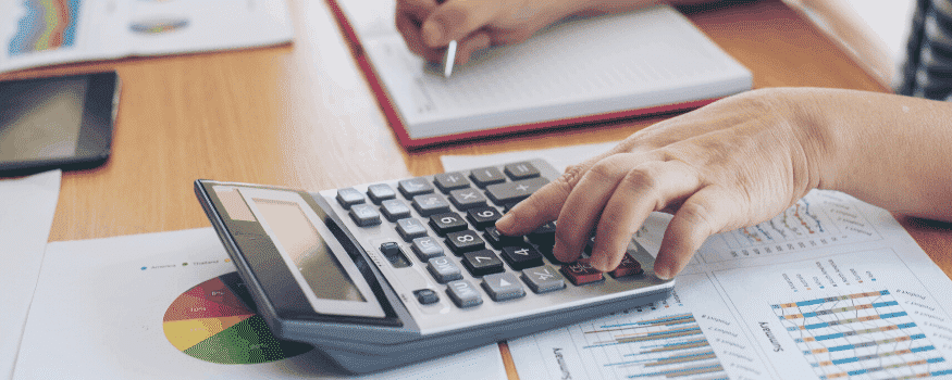 Uma pessoa fazendo contas com calculadora e anotando o dados em uma agenda.