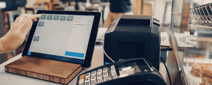 Uma pessoa realizando o fechamento de caixa por meio de um tablet e máquina de cartão.