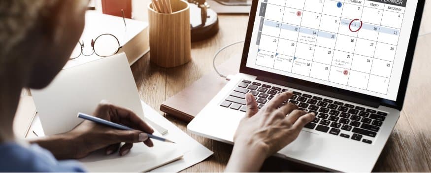 Uma mulher organizando seu tempo utilizando um notebook.