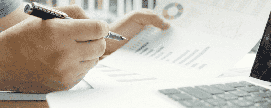Uma pessoa analisando um gráfico sobre ponto de equilíbrio e anotando as informações.