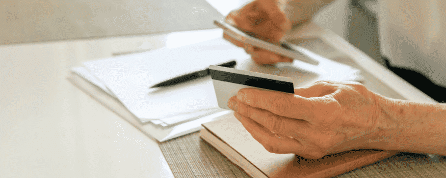 Uma pessoa verificando no celular a situação da recuperação de crédito com o cartão na mão.