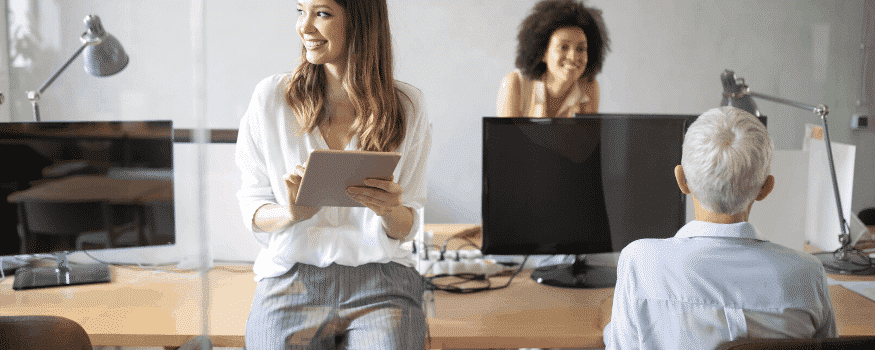 Três pessoas em uma sala de escritório aprendendo backoffice o que é.