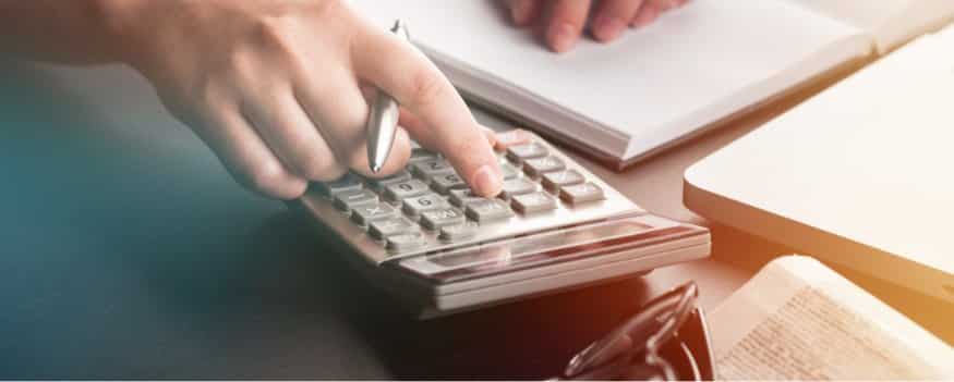 Uma pessoa fazendo calculo de folha de pagamento na calculadora.