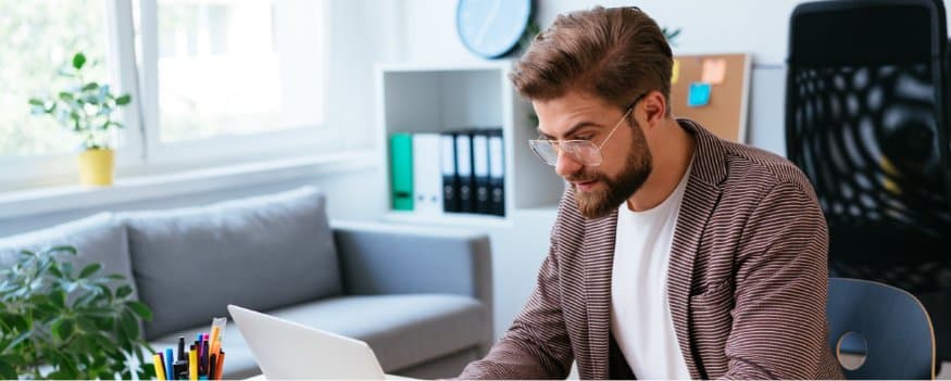 Um homem mexendo no notebook em um escritório.