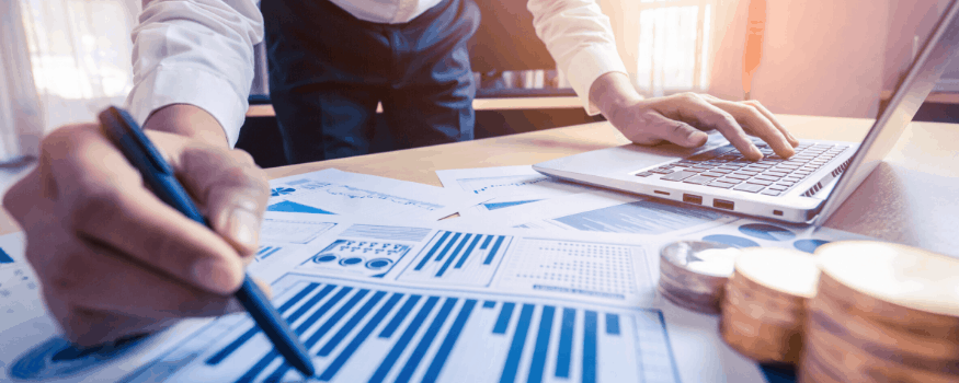 Uma pessoa analisando gráficos, mexendo no computador e analisando como conseguir empréstimo BNDES.