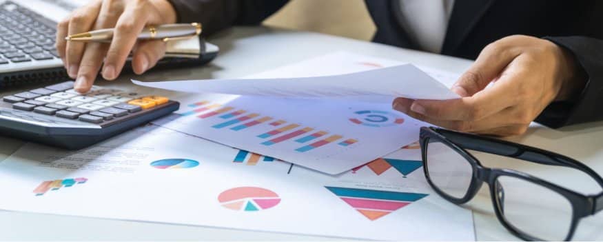 Uma pessoa analisando gráfico e fazendo contas com relação ao custo de produção de sua empresa.