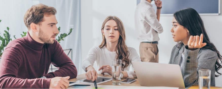 Três pessoas numa reunião com notebook.